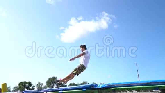 成年男子在蹦床上跳起来在空中旋转然后降落在他的肚子上再次弹跳动作缓慢视频的预览图
