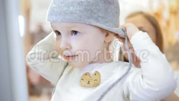 儿童的服装店带着妈妈购物买帽子的金发小女孩视频的预览图
