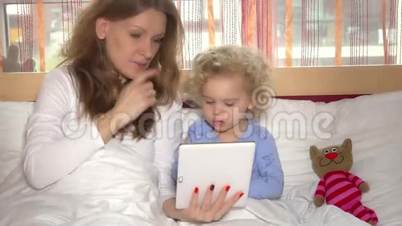 漂亮的妈妈和小可爱的女儿在玩平板电脑游戏视频的预览图