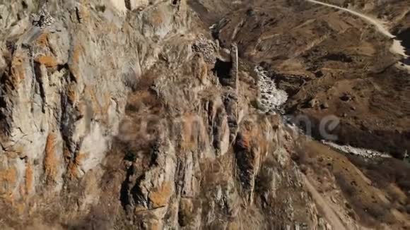 上巴尔卡里亚山上一块岩石上的古塔废墟从空中俯瞰峡谷有一条土路和视频的预览图