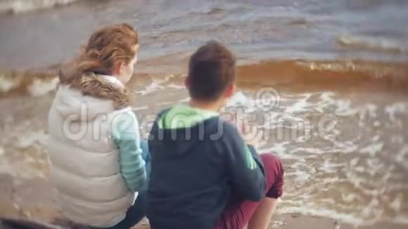 妈妈和儿子一起玩坐在海边的海边视频的预览图