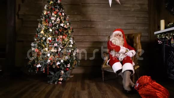 圣诞老人在家中的圣诞树旁拉书视频的预览图