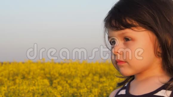 大自然中一个小女孩的脸孩子的脸是特写的这孩子穿着黄色的花油菜田视频的预览图