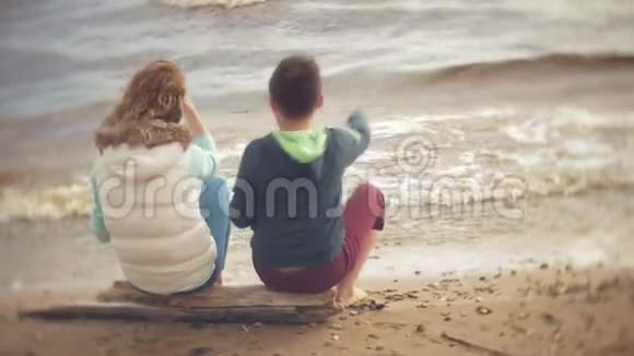妈妈和儿子一起玩坐在海边的海边视频的预览图