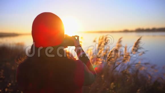 旅游少女旅行者女摄影师拍照少女拍海滩湖照片女人拍照视频的预览图