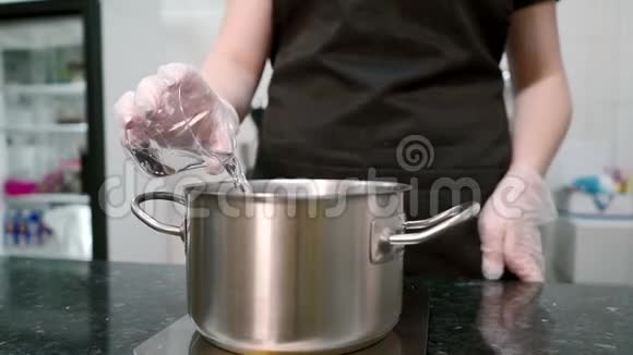 年轻的厨师在室内厨房里把水和糖倒进锅里视频的预览图