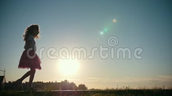 小女孩在公园里玩耍和散步日落时的剪影慢动作视频的预览图