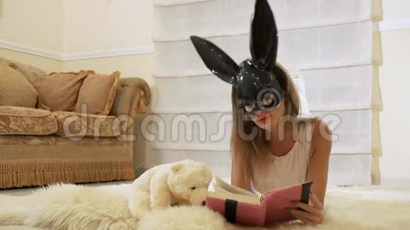 戴着兔子面具的女孩在地板上看书视频的预览图
