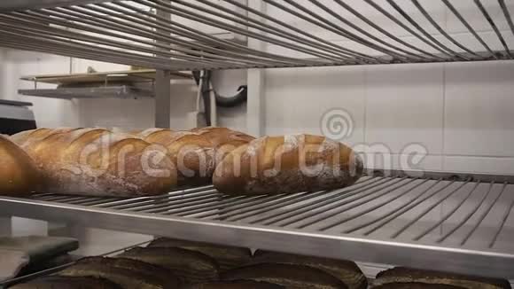 人们把新鲜的烤面包放在面包店的钢架上视频的预览图