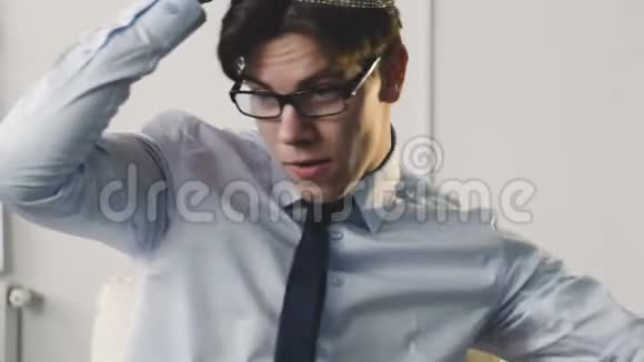 快乐的年轻人头上戴着皇冠在办公室的椅子上转悠视频的预览图