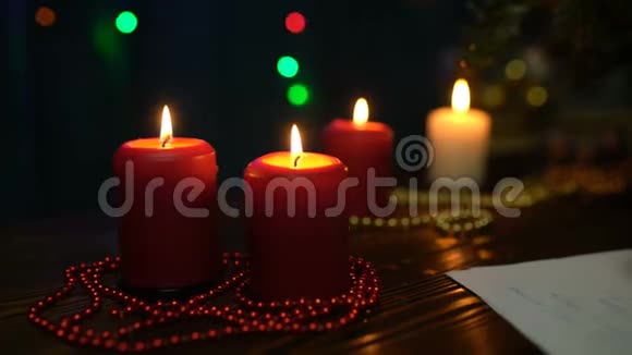 一个女孩在圣诞树彩灯和蜡烛的背景上签圣诞贺卡视频的预览图