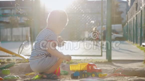 日落时分小男孩在沙箱里玩玩具视频的预览图