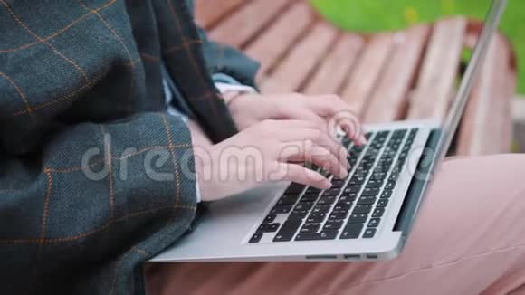 年轻女孩坐在长凳上拿着笔记本电脑学生准备考试视频的预览图