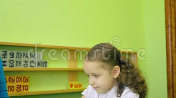 一个女孩在上课一个可爱的女孩和她的老师一起做功课用明亮的彩色铅笔4K视频的预览图