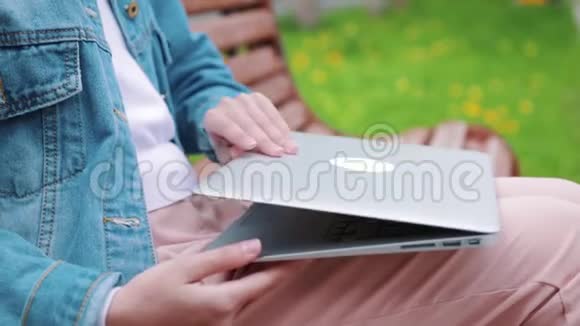 年轻女孩坐在长凳上拿着笔记本电脑学生准备考试视频的预览图