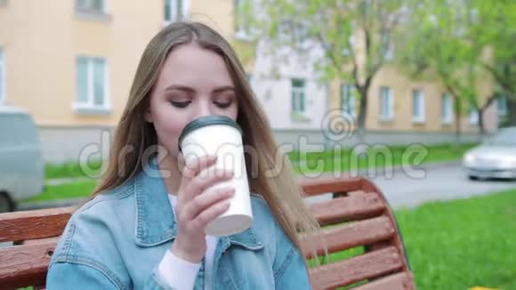 饮料和人的概念快乐的年轻女人或十几岁的女孩喝咖啡从纸杯坐在城市街道上视频的预览图