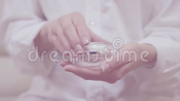 细嫩女人手的特写镜头打开护肤霜的玻璃瓶用按摩涂抹手与优雅的法国视频的预览图