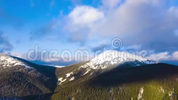 蓝天上的云层过度消散覆盖了高山雪山和针叶林的惊人景观视频的预览图