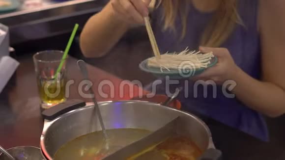 一个亚洲咖啡馆的年轻女子用火锅做饭食物放在小盘子上的传送带上食物传送带视频的预览图