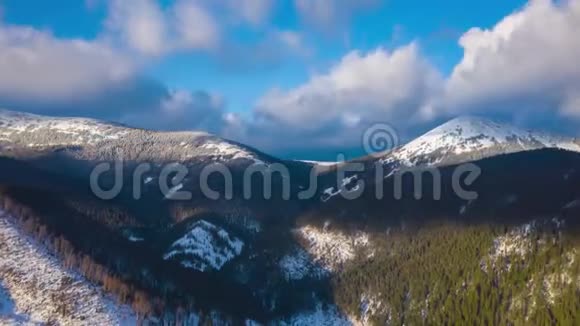 蓝天上的云层过度消散覆盖了高山雪山和针叶林的惊人景观视频的预览图