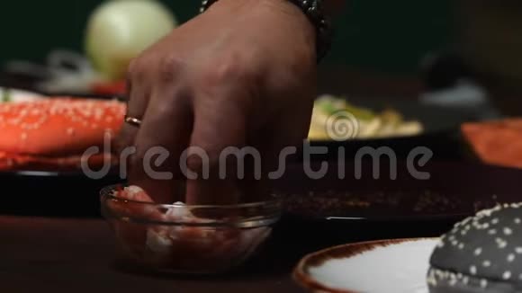 小碗的特写和虾男厨师穿着蓝色围裙吃几个虾然后把它们放进汉堡包里视频的预览图