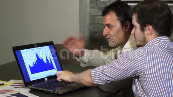 两位商务同事讨论笔记本电脑上的图表视频的预览图