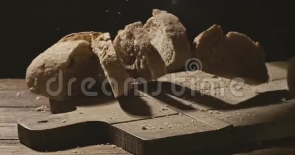 新鲜出炉的面包片落在木板上桌子落在黑暗的背景上视频的预览图