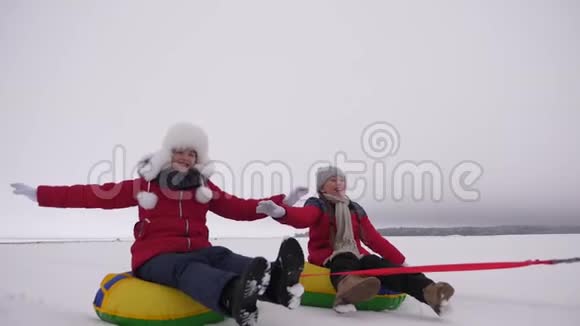 穿红色夹克的孩子们在冬天骑着充气雪管穿过雪地扮演超级英雄快乐的女孩视频的预览图