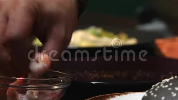小碗的特写和虾男厨师穿着蓝色围裙吃几个虾然后把它们放进汉堡包里视频的预览图