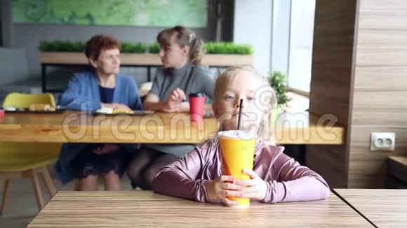 这个女孩在他母亲和祖母的背景下喝果汁视频的预览图
