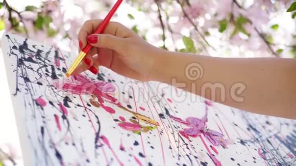 特写女手画家画家画家在盛开的春苹果园画了一幅花的画她涂上了油视频的预览图