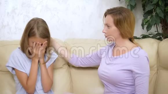 家庭支持和信任的概念妈妈拥抱并安慰坐在客厅沙发上的十几岁的女儿视频的预览图
