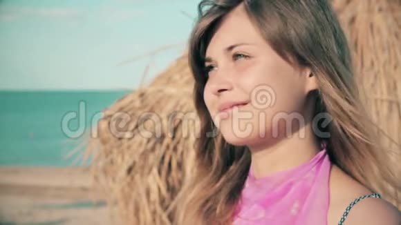 年轻女子抬头望着海滩在海边度假的慢动作视频的预览图