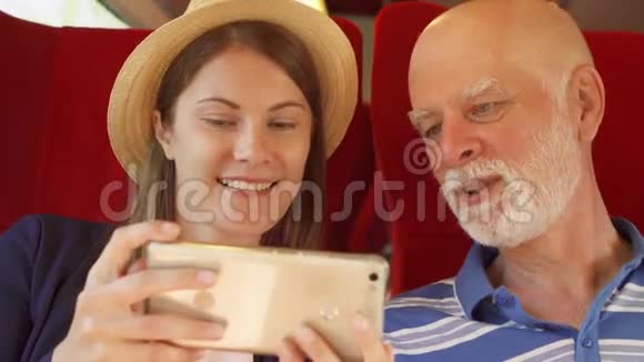 父亲和他的女儿在高速国际列车上使用智能手机退休后积极的现代生活快乐视频的预览图