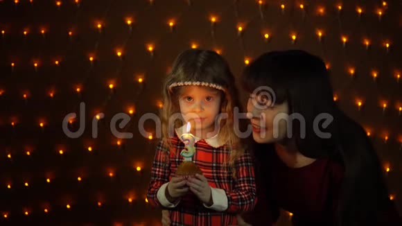 一个小女孩和她妈妈一起在节日蛋糕上吹蜡烛视频的预览图