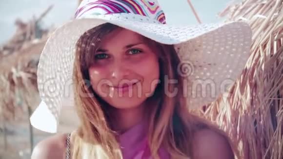 一个戴帽子的慢动作的年轻女人在海滩上给她心爱的人一个空中亲吻视频的预览图