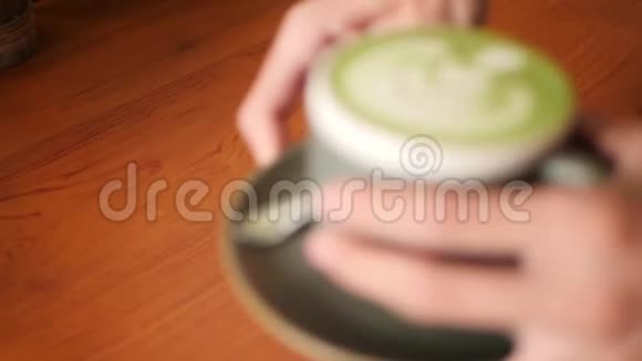 咖啡师把一杯抹茶绿茶放在咖啡店的木桌上4K慢动作视频的预览图