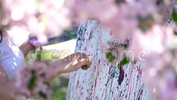 特写女手画家艺术家在盛开的春天苹果园里画花她画画视频的预览图