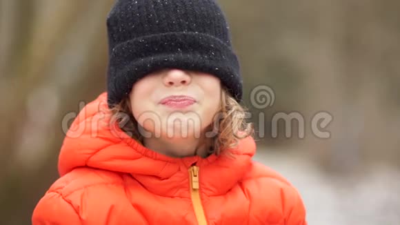 一个穿冬织帽子的男孩的肖像他用帽子闭着眼睛笑视频的预览图