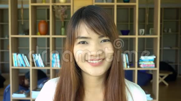 微笑美丽的亚洲学生站在图书馆的肖像背景书架视频的预览图
