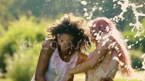 美丽的年轻女人拥抱着微笑着水溅在快乐的女人身上视频的预览图