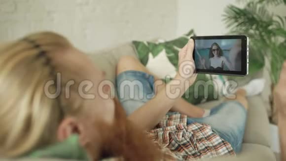 小胡子男和女朋友在家里的沙发上用平板电脑聊天视频的预览图
