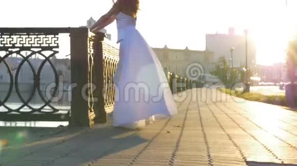 一个穿着白衣的美丽女孩在城市的堤岸上迎着黎明清晨美好的一天视频的预览图