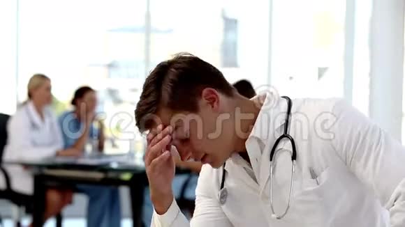 年轻的忧心忡忡的医生抱着他的头视频的预览图