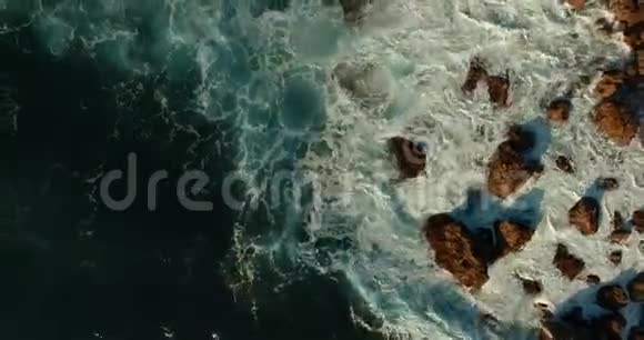 海浪拍打在石头上像新年香槟一样飞溅视频的预览图