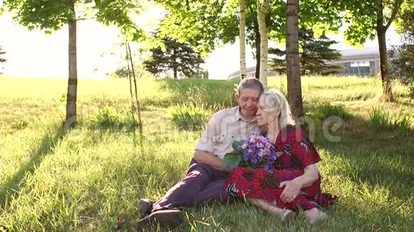 80岁的祖父母坐在公园的草地上视频的预览图