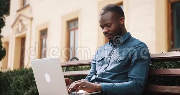 非裔美国人商务人员坐在长凳上在笔记本电脑上工作视频的预览图