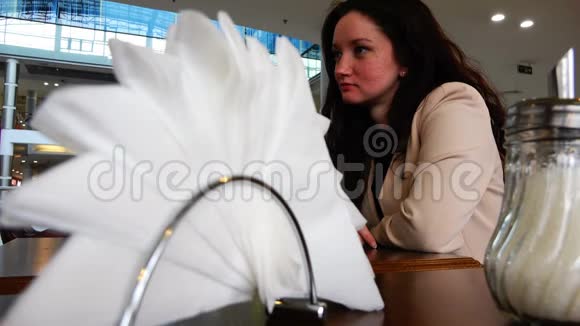 穿着夹克衫的布鲁内特笑着坐在咖啡馆的桌子旁视频的预览图