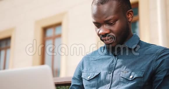 非裔美国人商务人员坐在长凳上在笔记本电脑上工作视频的预览图