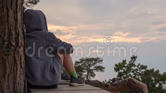 一个身穿连帽衫的电影摄影女孩坐着凝视着天空4k时间间隔视频的预览图